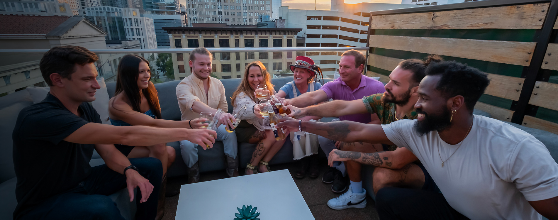 Group of Maddox guests sharing a rooftop toast at sunset over downtown Nashville